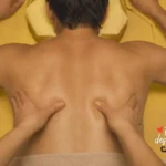 Deux mains qui massent le dos d'un homme